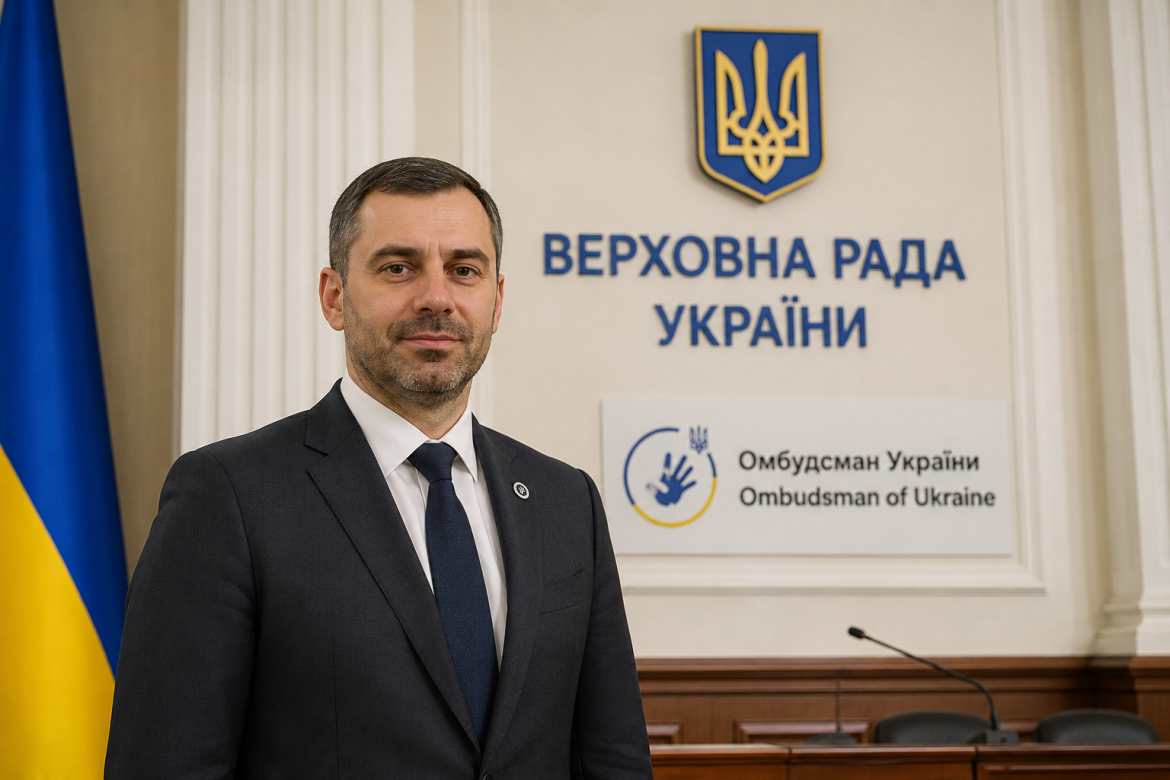 Чоловік у діловому костюмі стоїть на тлі напису «Верховна Рада України» та логотипу Омбудсмана України з українським прапором